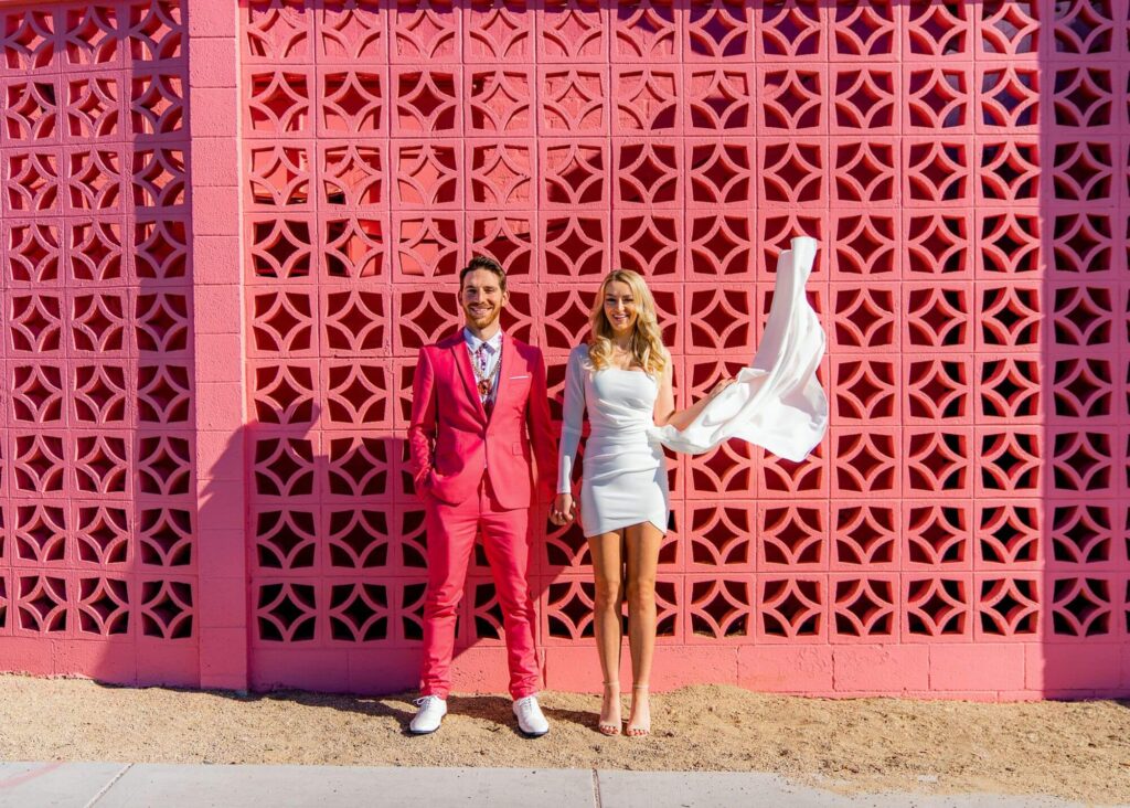 elopement photographer capturing a picture of newlyweds posing in front of a pink gate